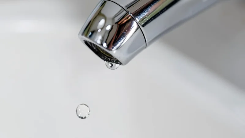 Primer plano de grifo monomando con gota de agua suspendida y cartucho cerámico